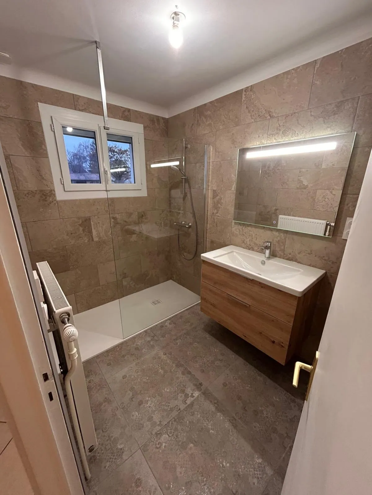 Salle de bain rénovée aux tons neutres : douche à l'italienne, meuble vasque bois et miroir lumineux