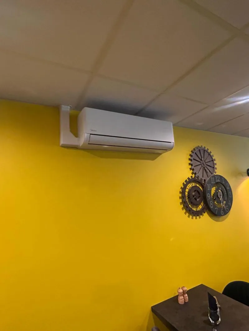 Climatiseur mural sur un mur jaune dans un restaurant