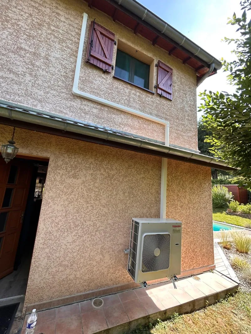 Groupe extérieur de climatisation au pied d'une maison