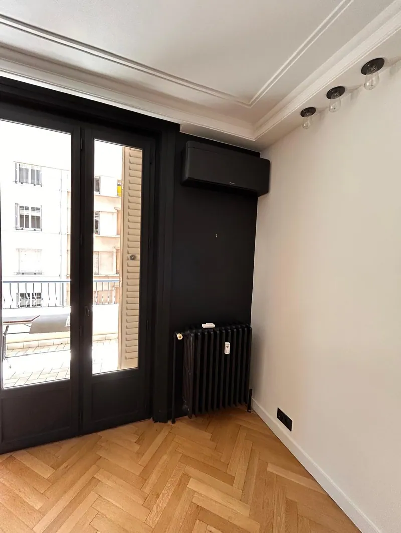 Climatiseur noir au-dessus d'une porte-fenêtre dans un appartement ancien